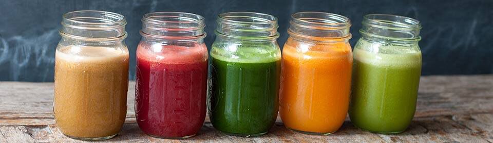 colorful smoothie drinks in glass jars on a countertop